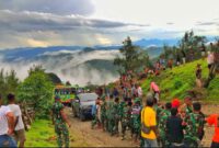 Wadansatgas Yonif 743/PSY bersama anggota dan masyarakat, saat mengevakuasi kendaraan masyarakat yang terjebak lumpur di jalan poros Oepoli (Foto : Dok. Dansatgas Pamtas RI - RDTL Yonif 743/PSY)