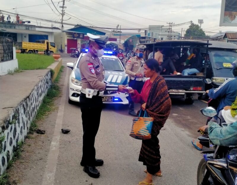 Personil Satlantas Polres Ende sedang membagikan masker kepada seorang Ibu di Pasar Mbongawani